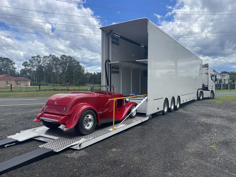 A classic car loaded onto a dedicated, fully enclosed trailer